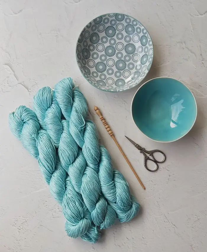 Knitting essentials including blue yarn and tools arranged on a textured surface, perfect for a crafting day.